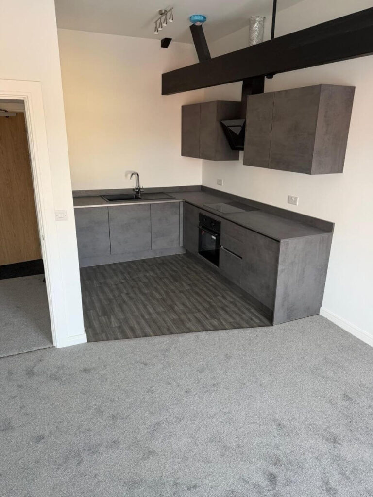 Grey vinyl tile flooring and grey carepts installed in the open plan living area / kitchen at the flats at Allinson House in Northampton.